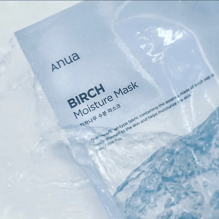 Bilden visar en förpackning av "Anua Birch Moisture Mask". Förpackningen är i mjukt blått och texten är både på engelska och koreanska. Produkten beskrivs som en fuktgivande ansiktsmask gjord av björksav, avsedd att ge näring och fukt till huden.